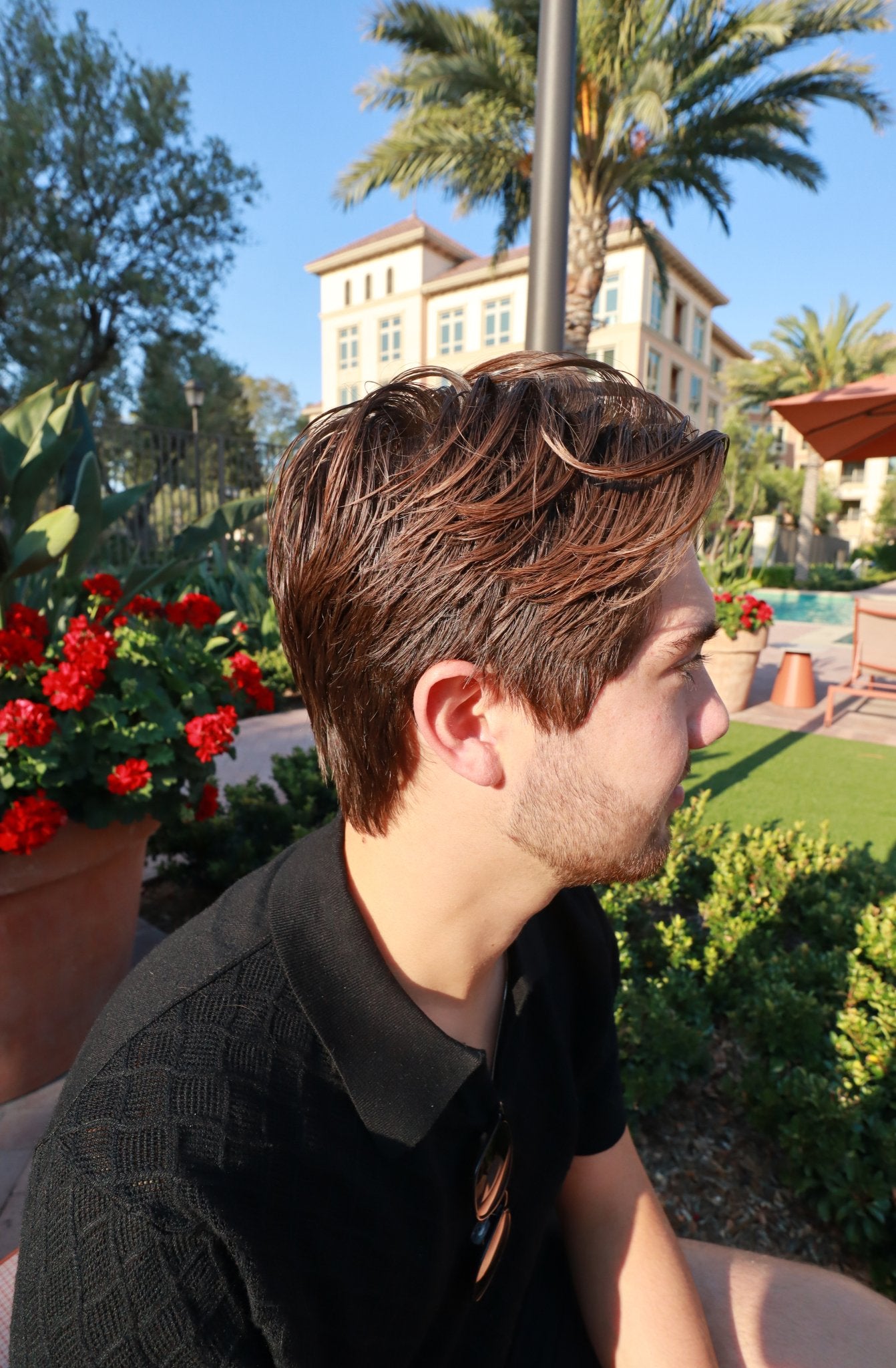 Man with perfectly styled hair using the best men's hair clay, Arctic Clay Pomade, sitting outdoors on a sunny day.